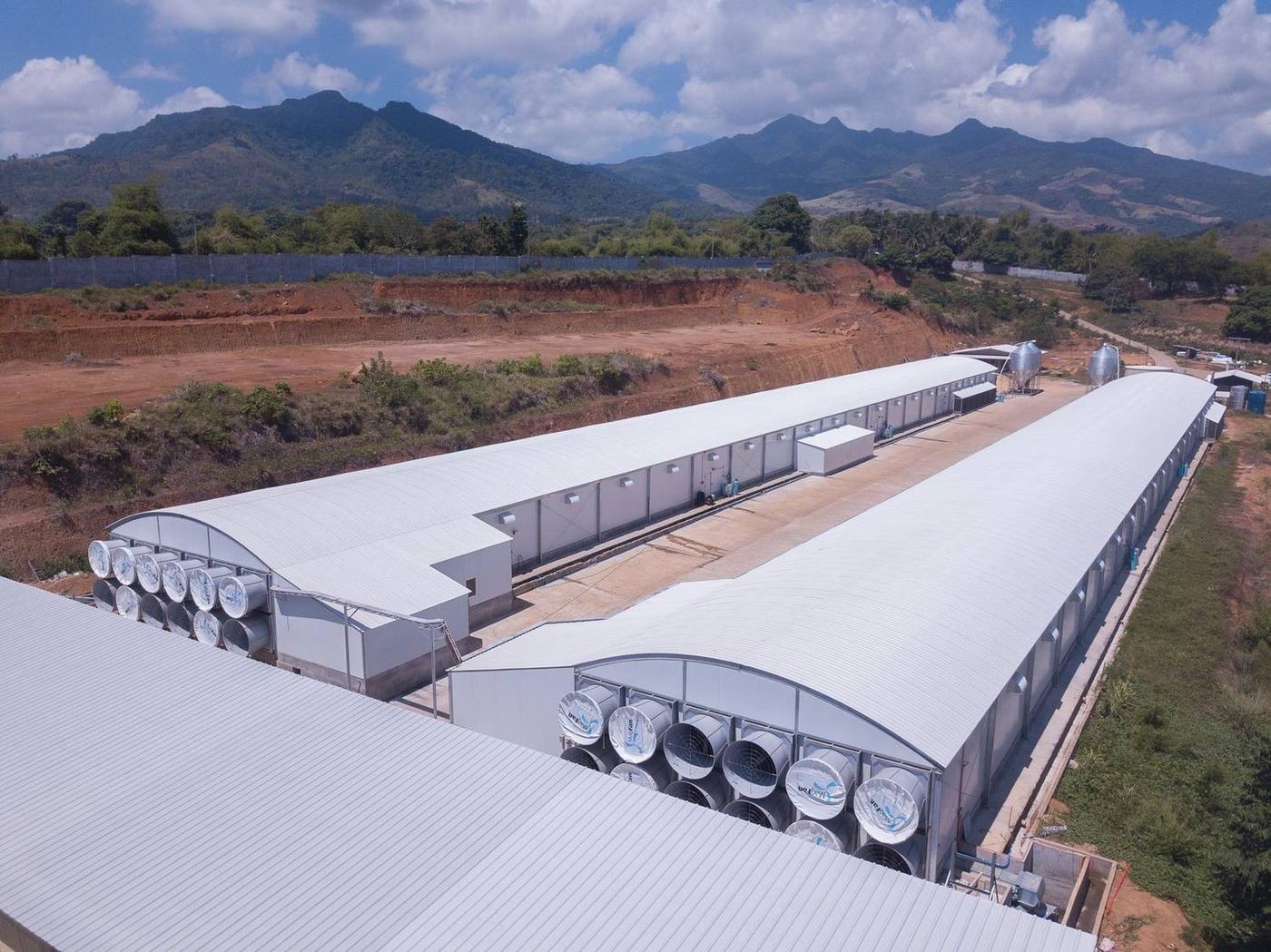 Aerial view of a poultry farm complex delivered by the group, with mountains behind